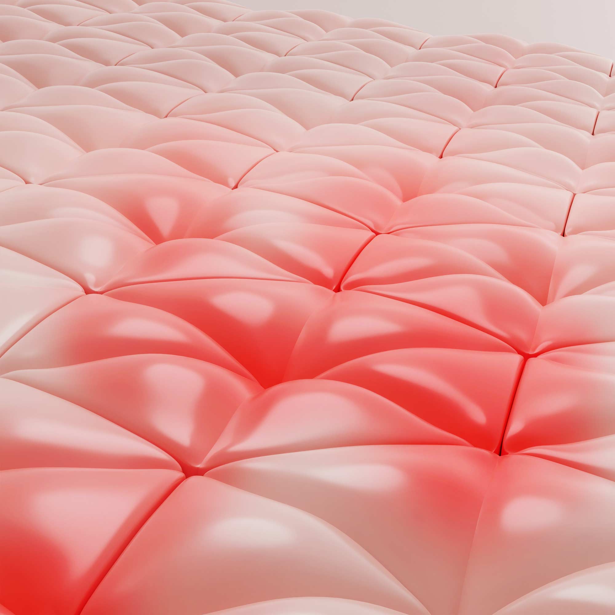 A close-up of a quilted tufted surface with a glossy finish, showing a color gradient from pale blush pink at the top to coral-red at the bottom.